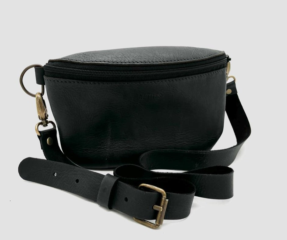 Black leather crossbody bag with a zipper closure and a detachable strap, isolated on a white background.