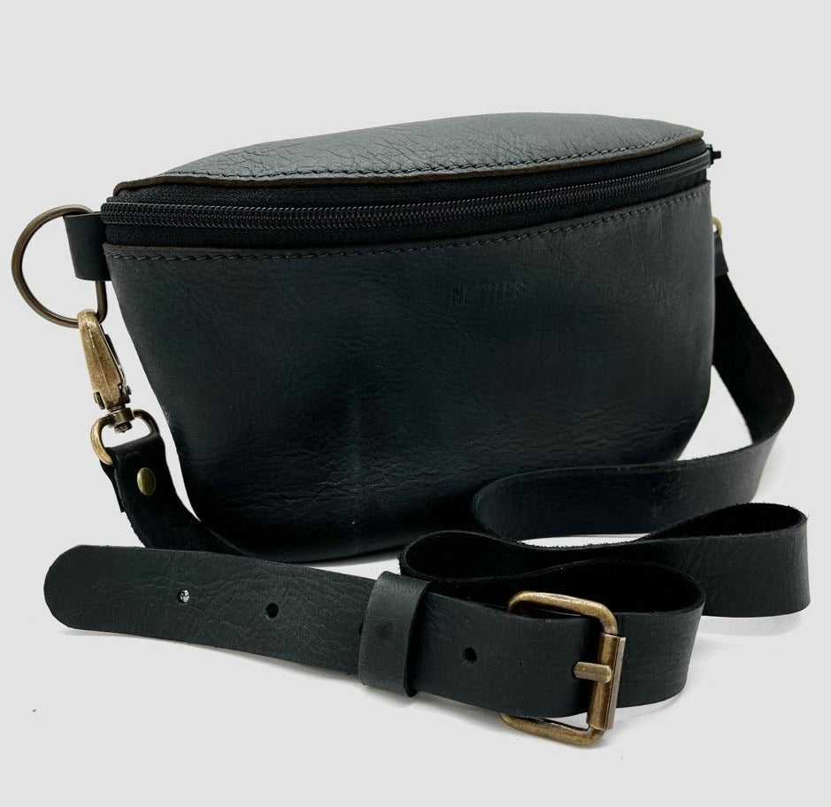Black leather crossbody bag with a zipper closure and a detachable strap, isolated on a white background.