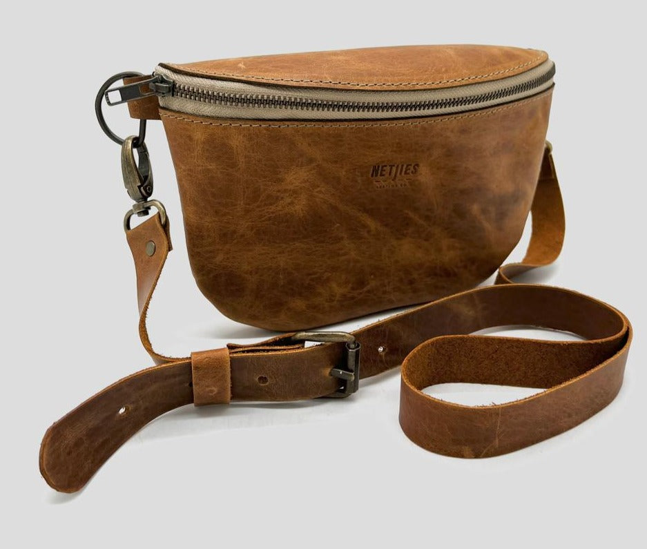 Brown leather crossbody bag with a zipper closure and a detachable strap, isolated on a white background.