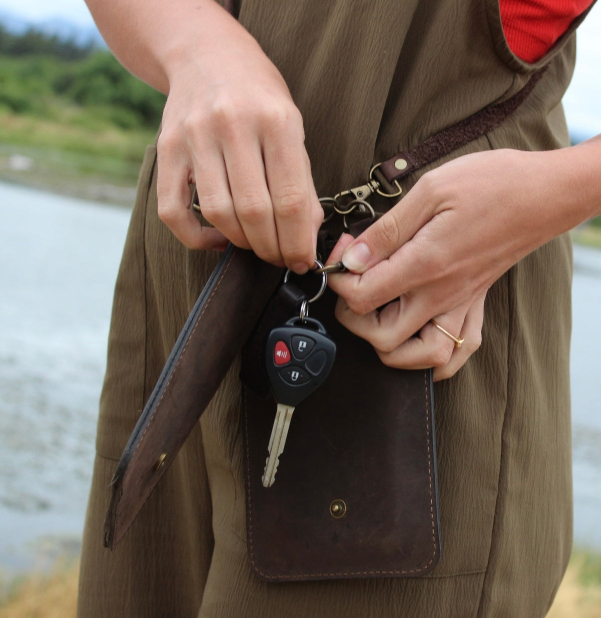 Person holding a brown leather bag with a blurred natural background