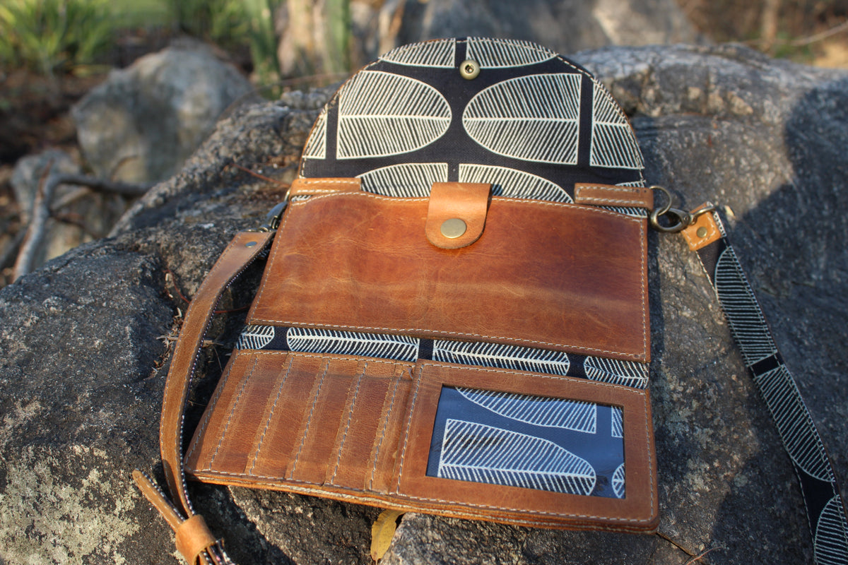Brown leather bag with geometric pattern on a rocky surface