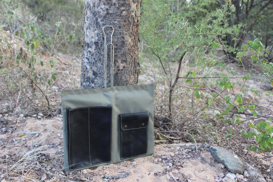 A green canvas bag hanging from a tree in a natural outdoor setting.